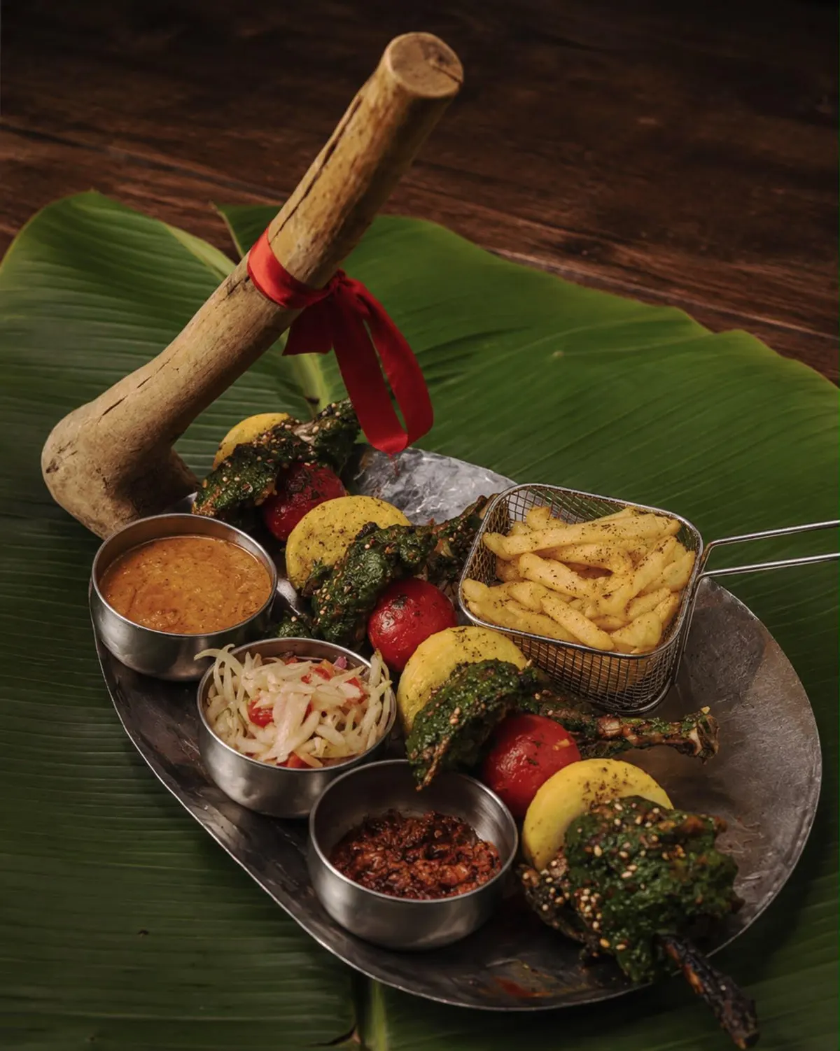 Plateau de brochettes, frites et sauces en coupelles, une hache en bois plantée dans le dressage