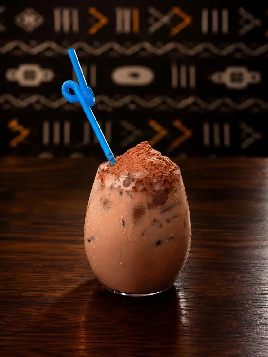 Boisson glacée au cacao, saupoudrée de chocolat, paille bleue