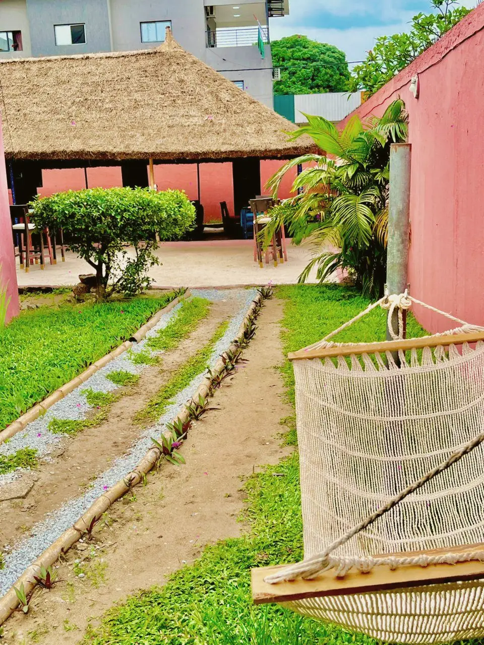 Hamac tressé au bord de l’allée du jardin, paillote en arrière-plan