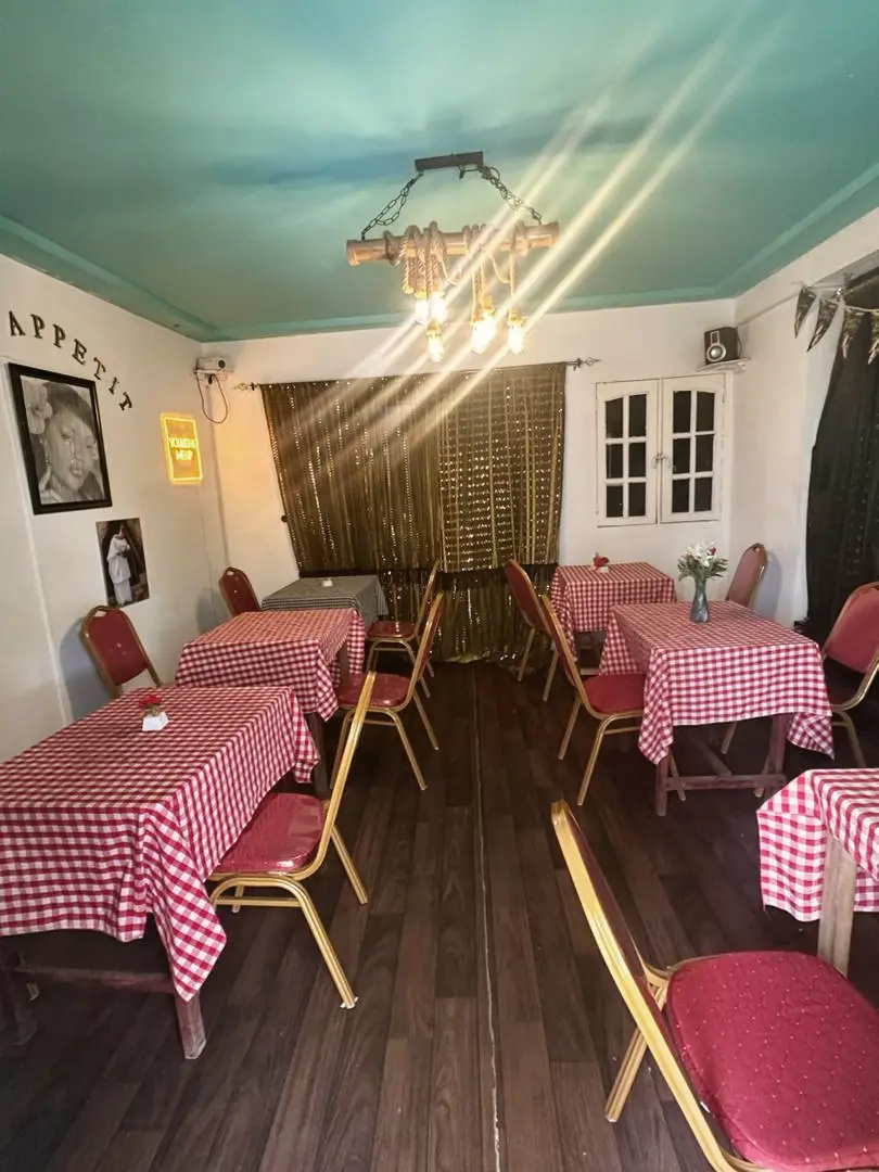 Salle intérieure aux nappes vichy rouges, plafond turquoise et lustre en bambou